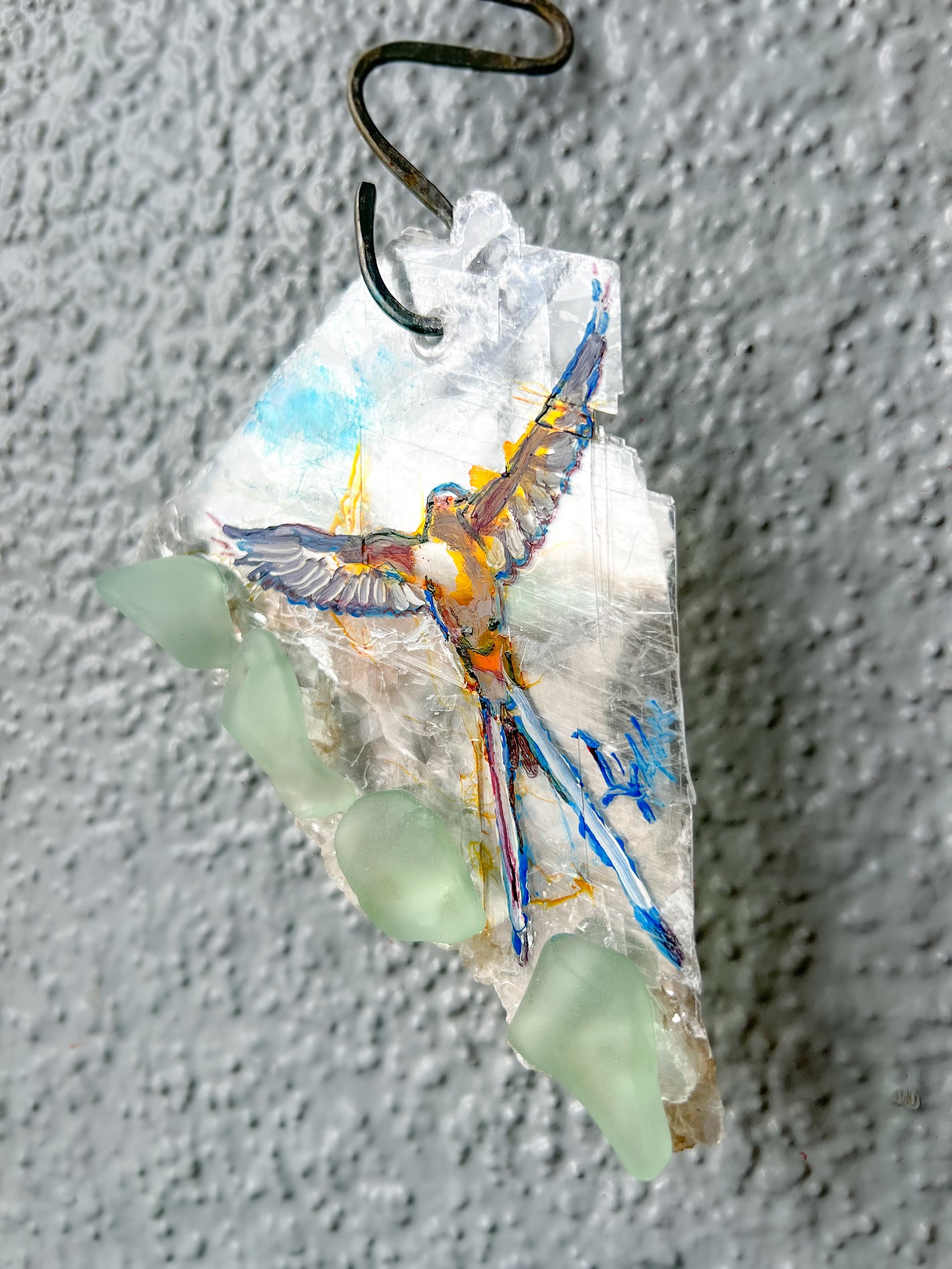 An image of a scissortail bird delicately painted on a piece of natural selenite crystal and adorned with tumbled glass pieces